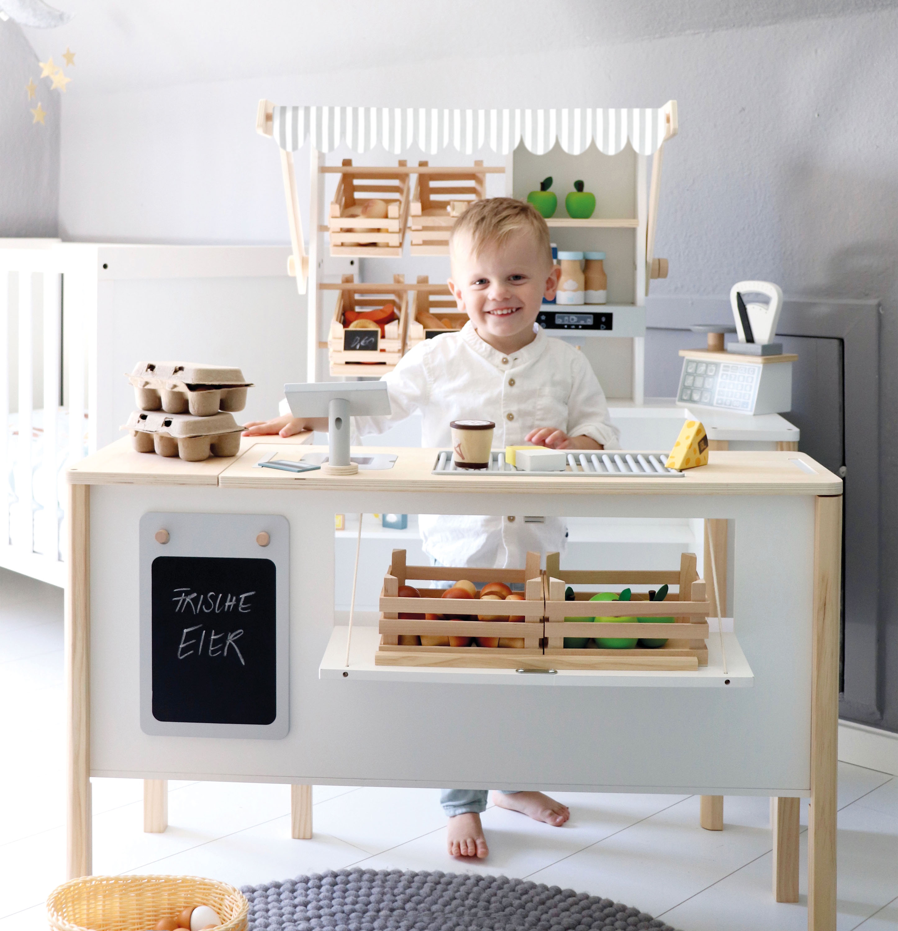 Junge spielt mit Kaufmannsladen aus Holz, Kinderkiosk, Holzspielzeug, Sortiment, Käse, Eier