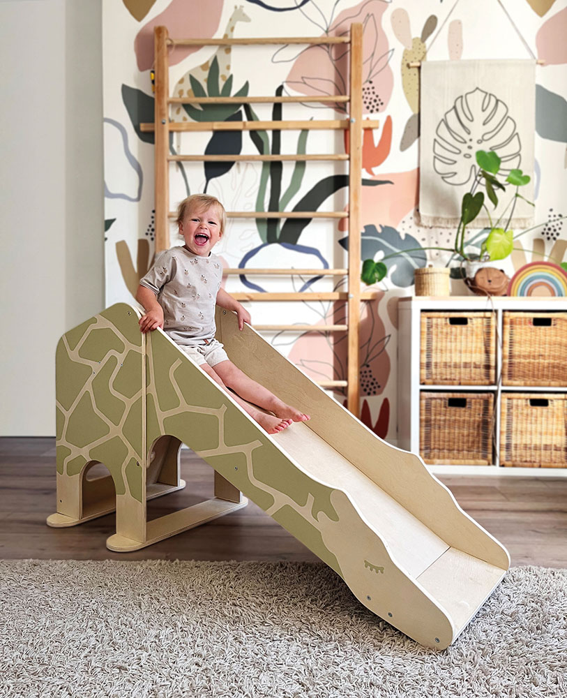 Kind rutscht Indoor-Giraffenrutsche hinunter