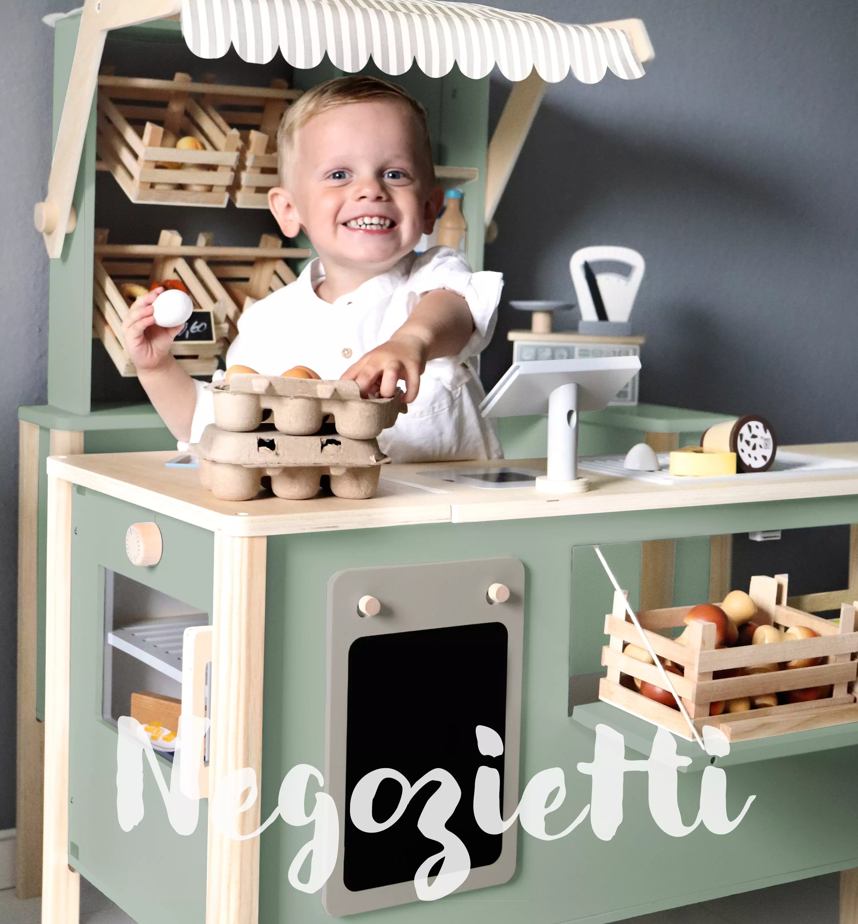 Junge spielt mit einem Kaufmannsladen aus Holz