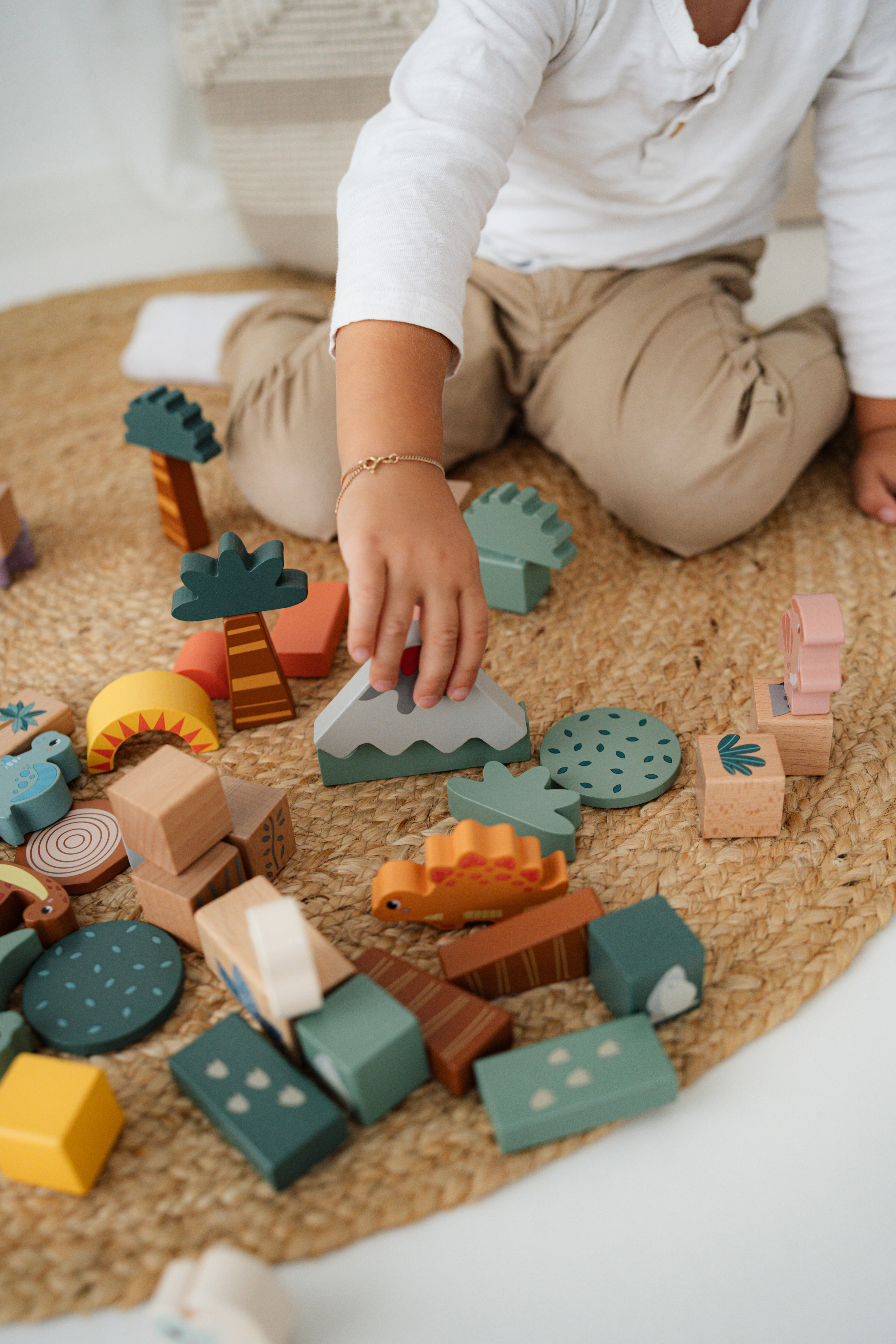 Kind spielt mit Holzbausteine Dino