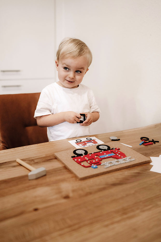 Kind spielt mit dem Hämmerchenspiel „Fahrzeuge der Stadt“