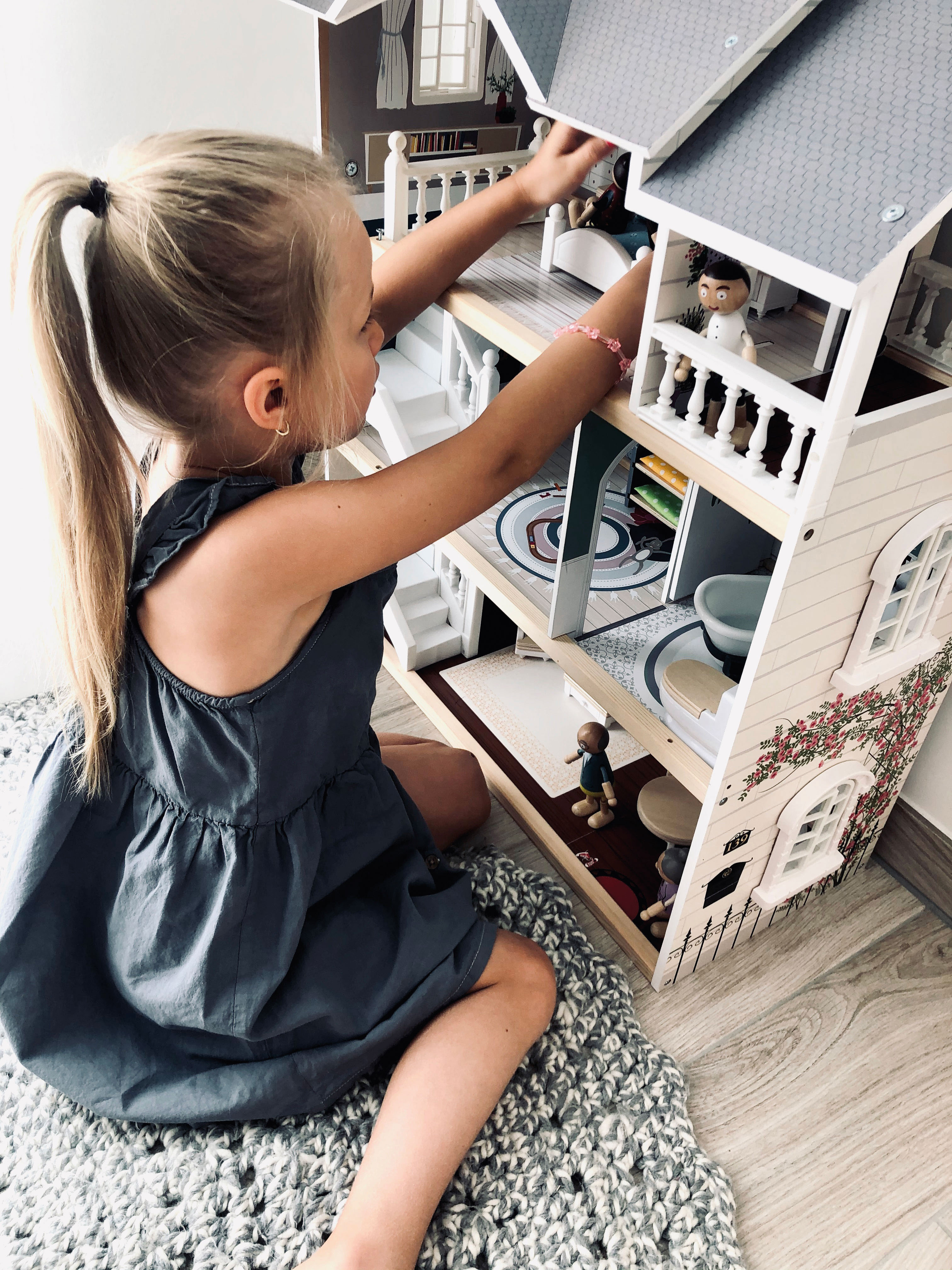 Mädchen mit großem Puppenhaus aus Holz