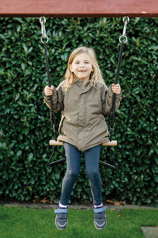 Kind schaukelt auf Trapezschaukel Ringe