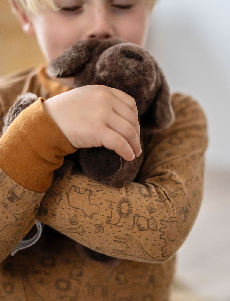 Kind spielt mit Plüschhund, Tasche und Pflegeset