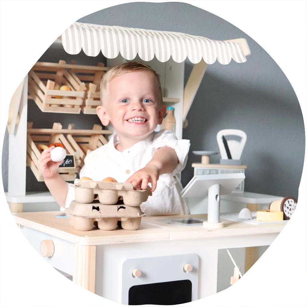 Junge spielt mit Kaufladen aus Holz