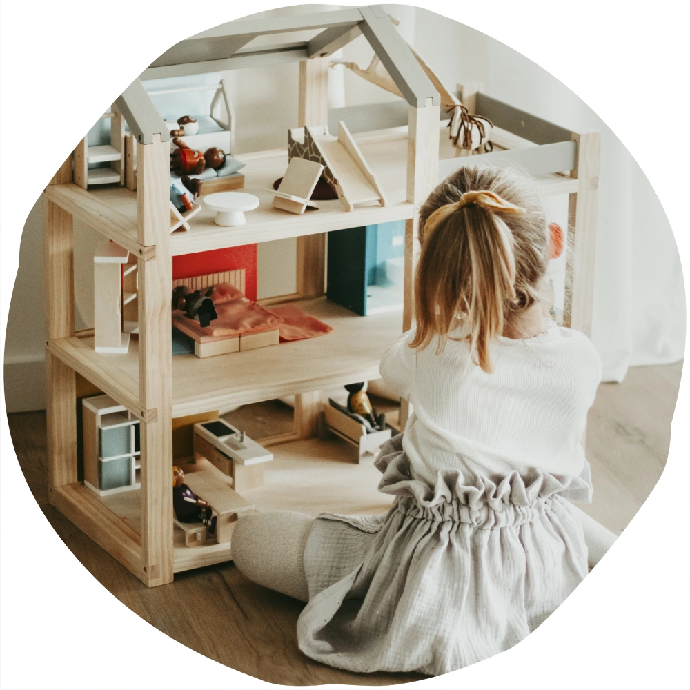 Mädchen spielt mit Puppenhaus