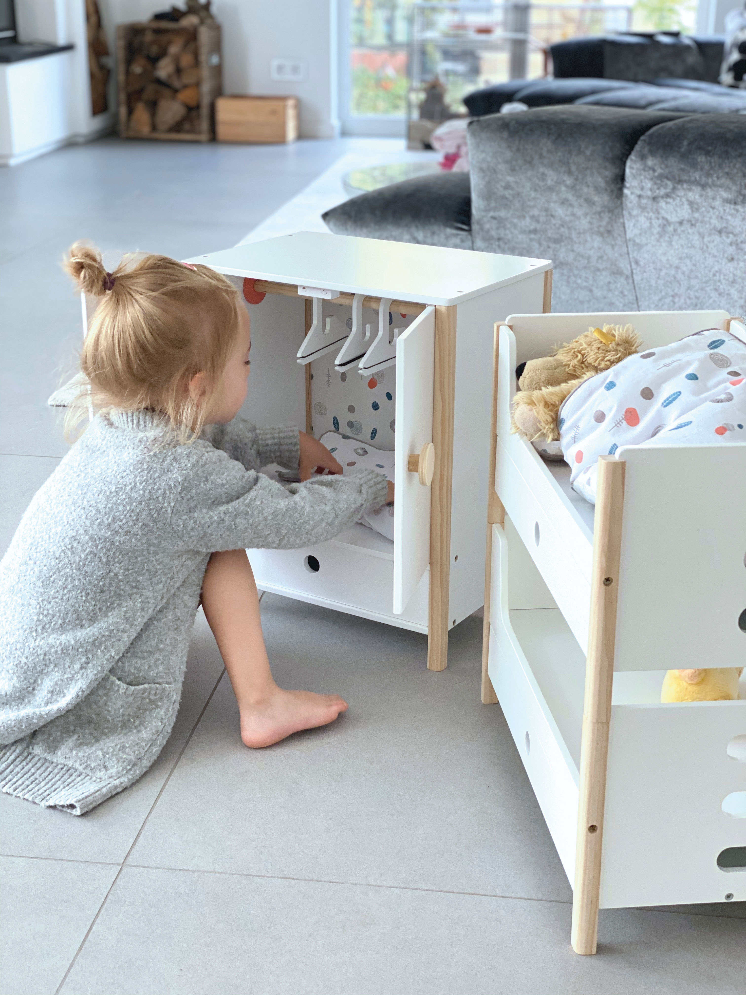 Kind spielt mit Puppenmöbeln aus Holz