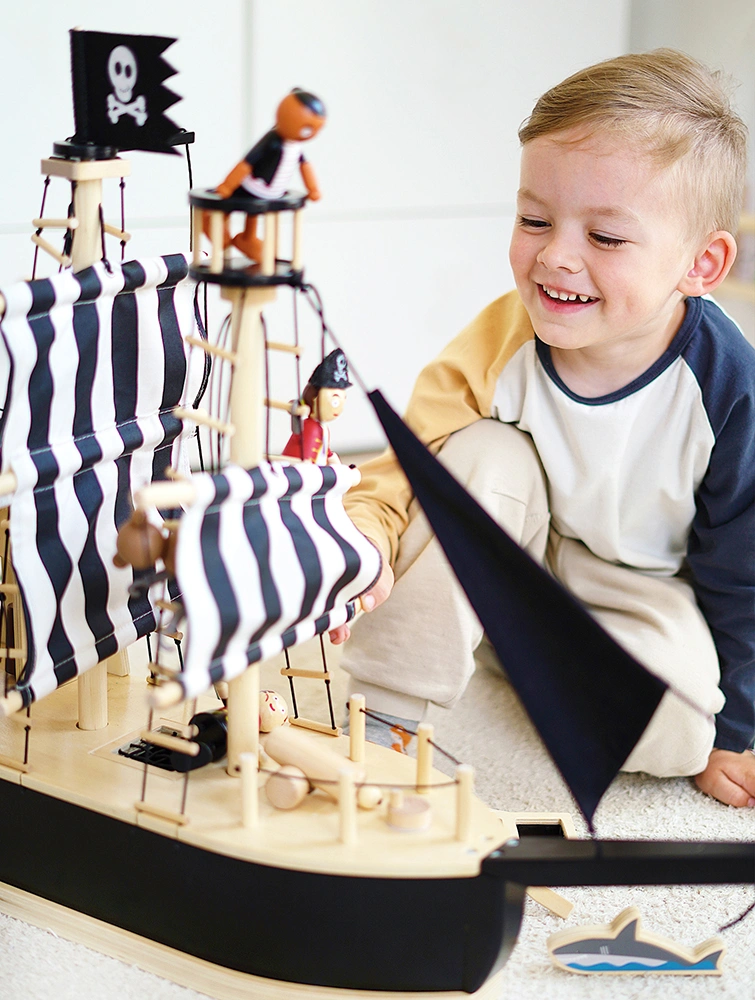 Junge spielt mit Piratenschiff aus Holz