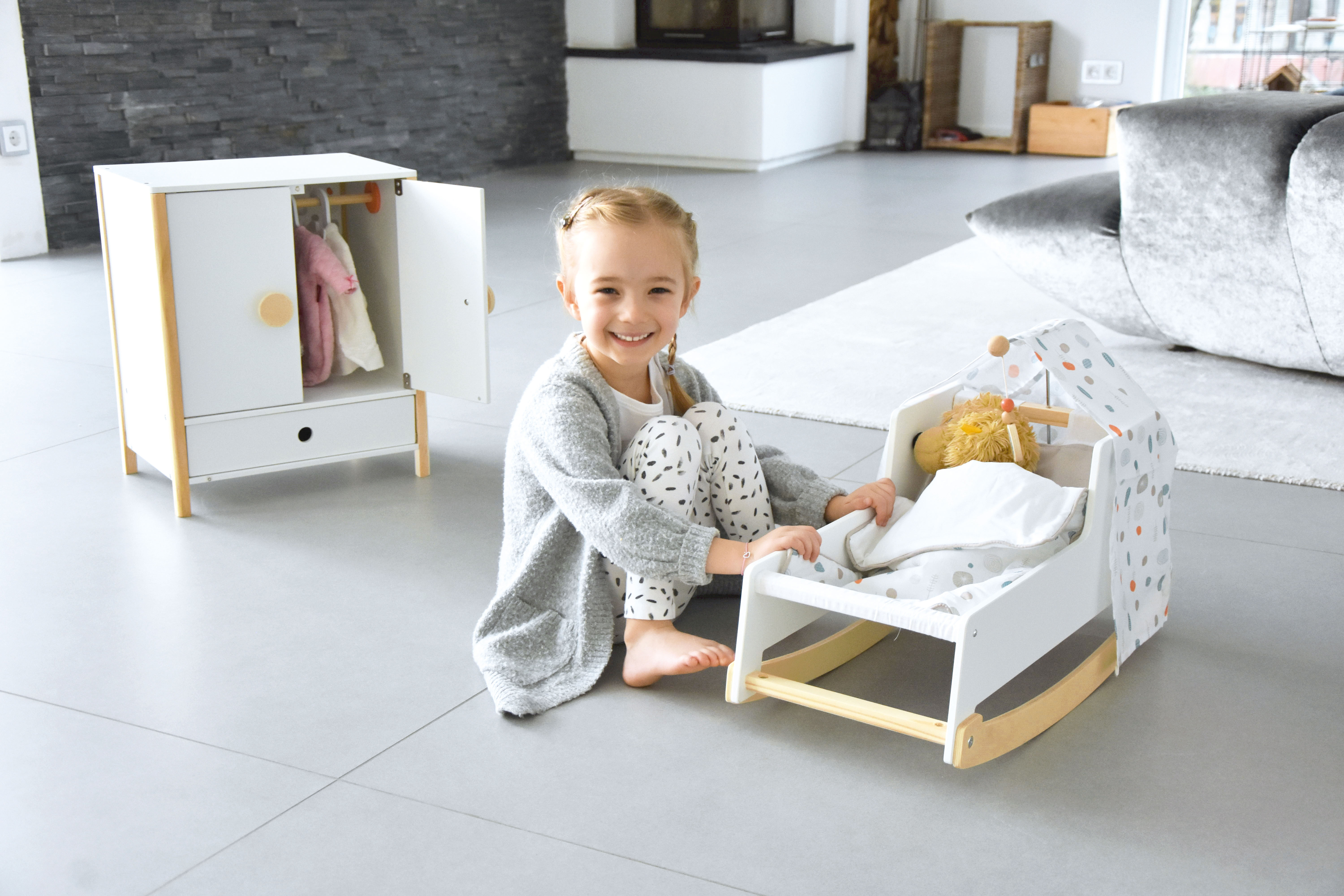 Mädchen mit Puppenwiege aus Holz zum Spielen