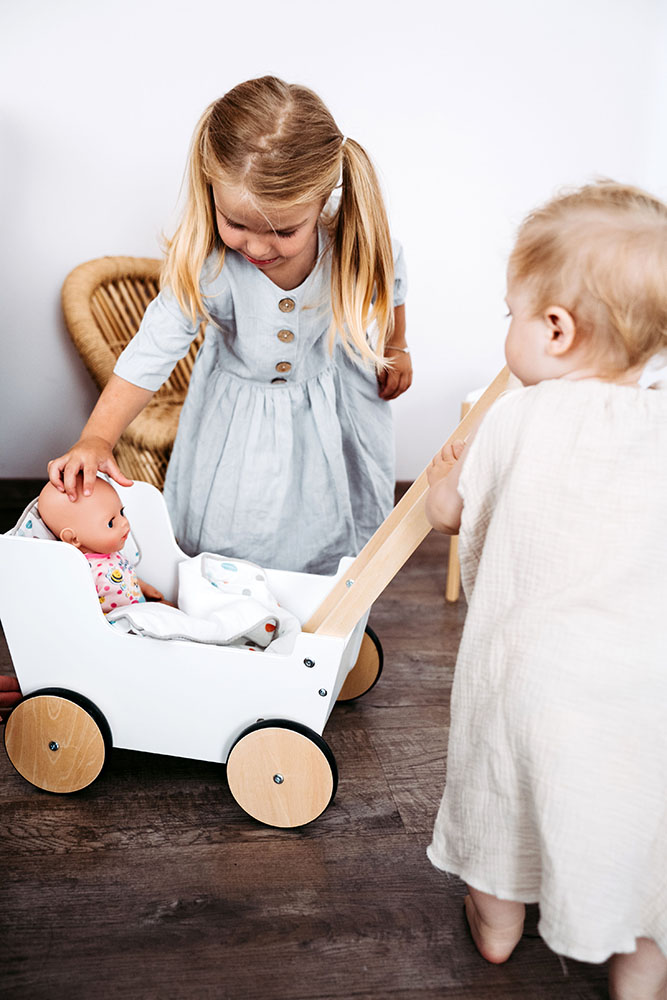 Kind spielt mit Schiebe- und Puppenwagen Little Button