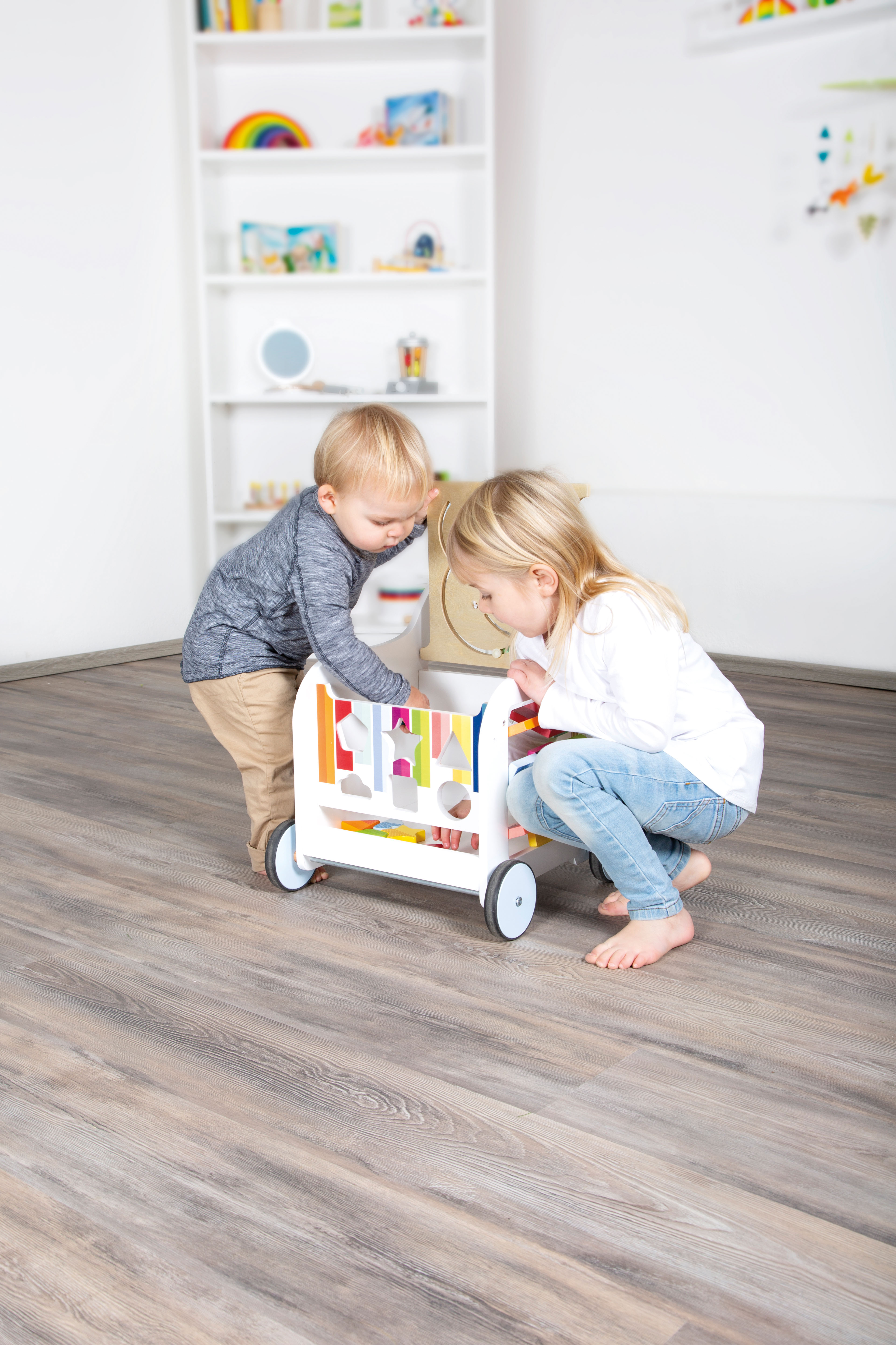 Kinder mit Regenbogen-Lauflernwagen aus Holz
