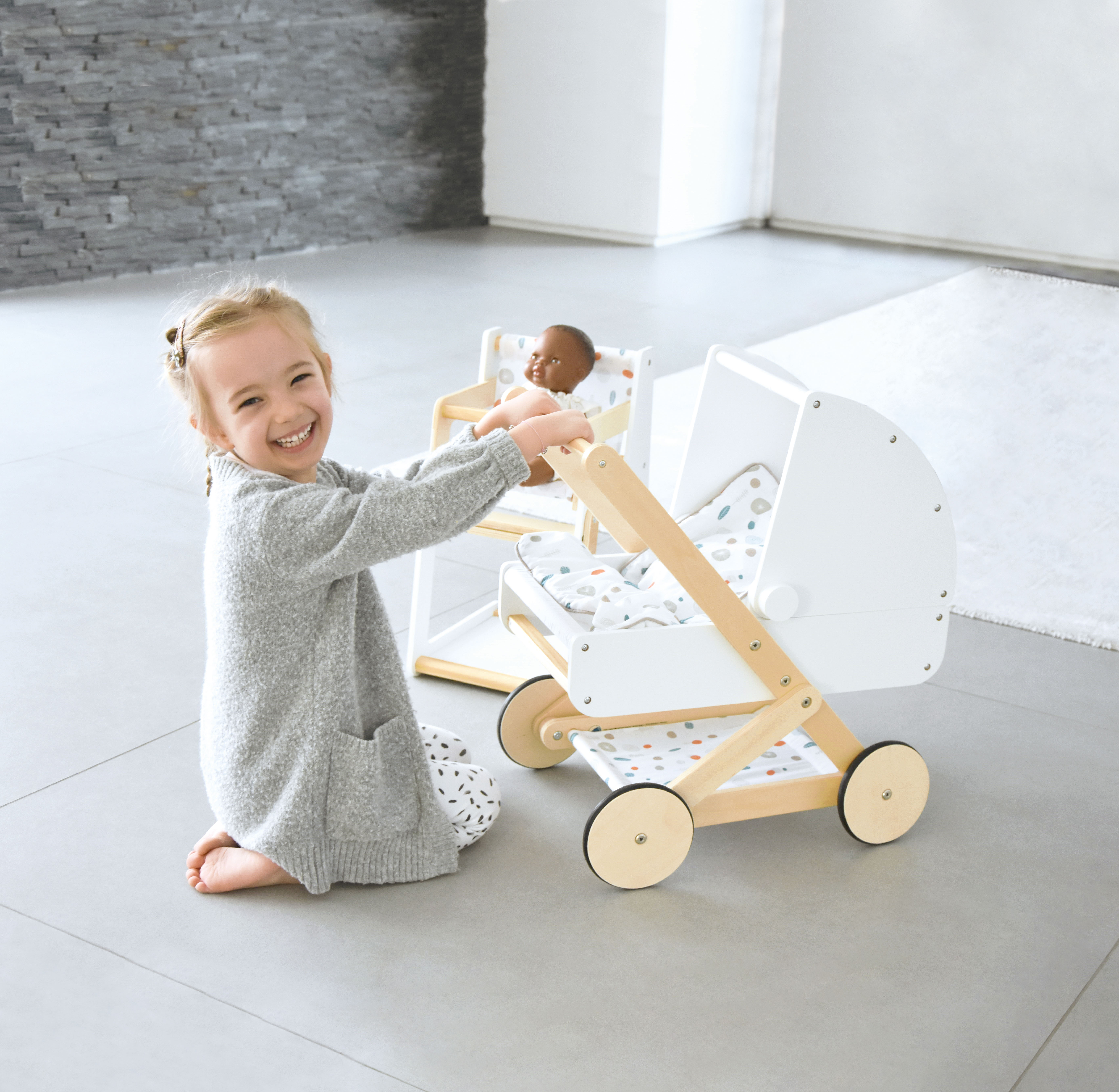 Mädchen mit Puppenhochstuhl und Schrank aus Holz