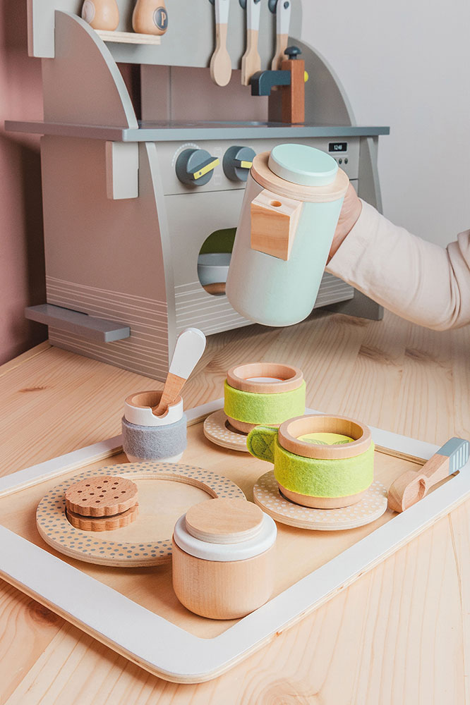 Kind spielt mit Kaffee- und Tee-Set Kinderküche