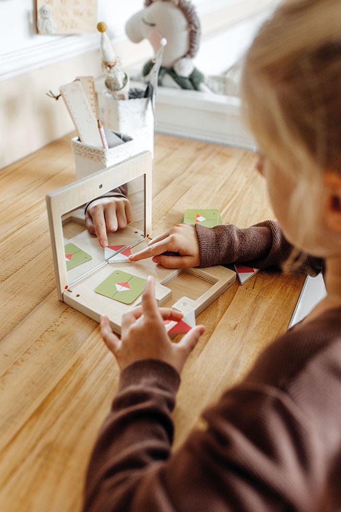 Kind spielt mit dem Symmetriespiel Educate und Spiegel