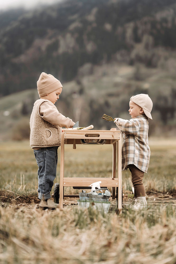 Kind spielt mit einer Gartentasche und passendem Gartenwerkzeug