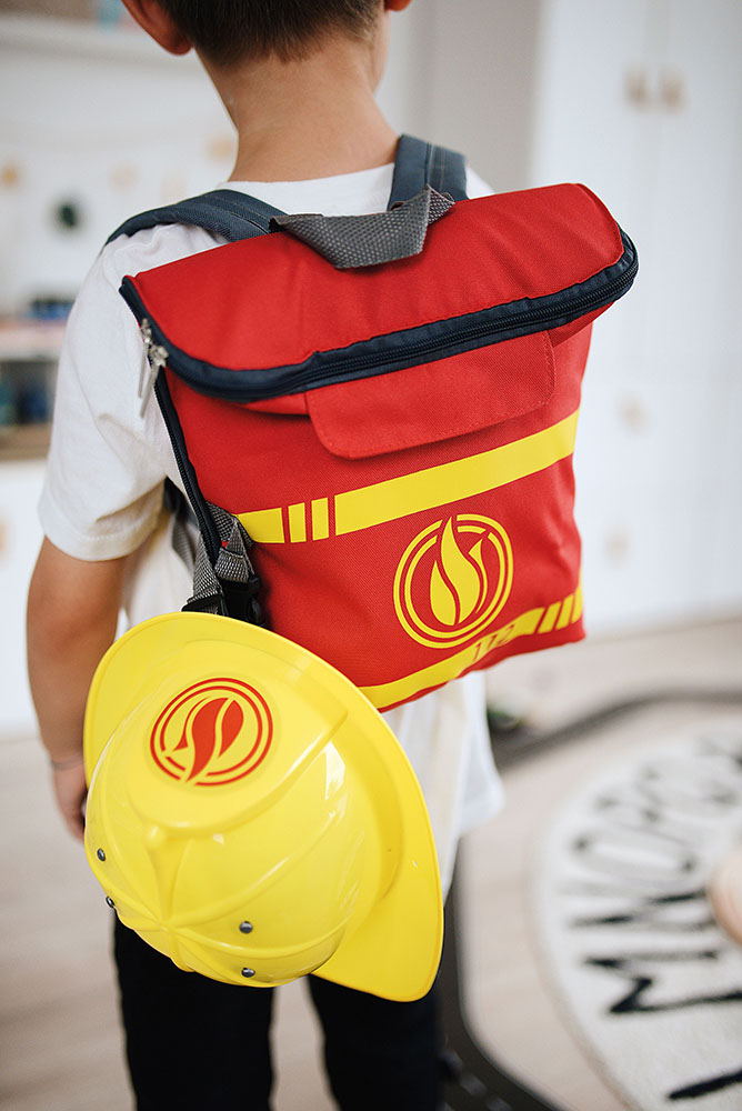 Kind spielt mit einem Feuerwehrrucksack