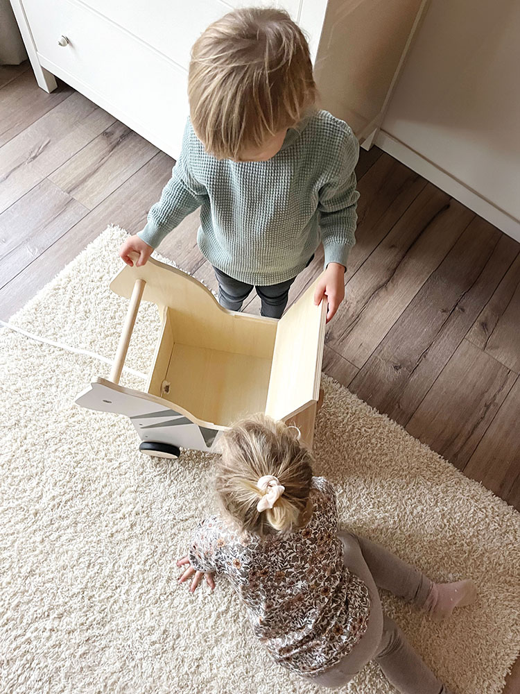 Kind zieht Zebra-Spielzeugkiste mit Rollen