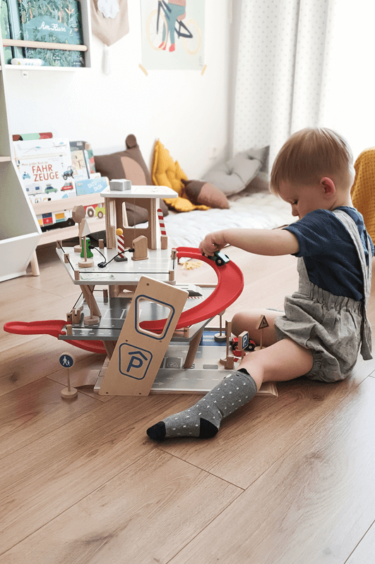 Kind spielt im Kinderzimmer mit Parkhaus