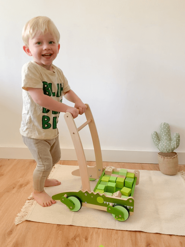 Kind mit grünem Krokodil-Lauflernwagen