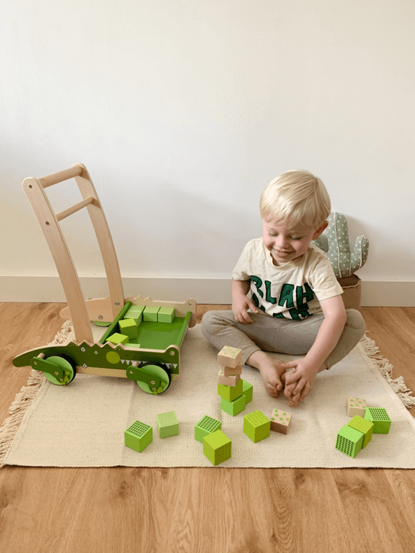 Kind spielt mit Bausteinen von Lauflernwagen