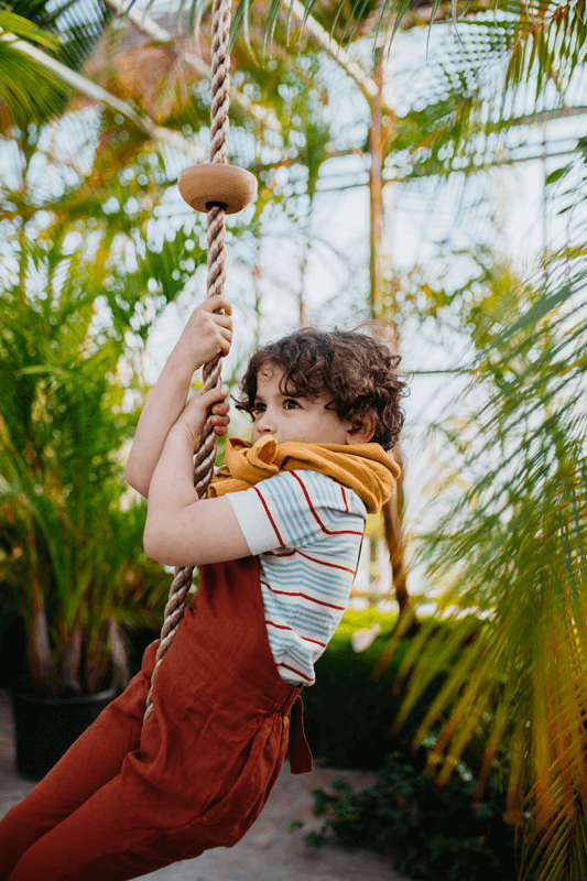 Junge schaukelt mit einem naturfarbenen Kletterseil