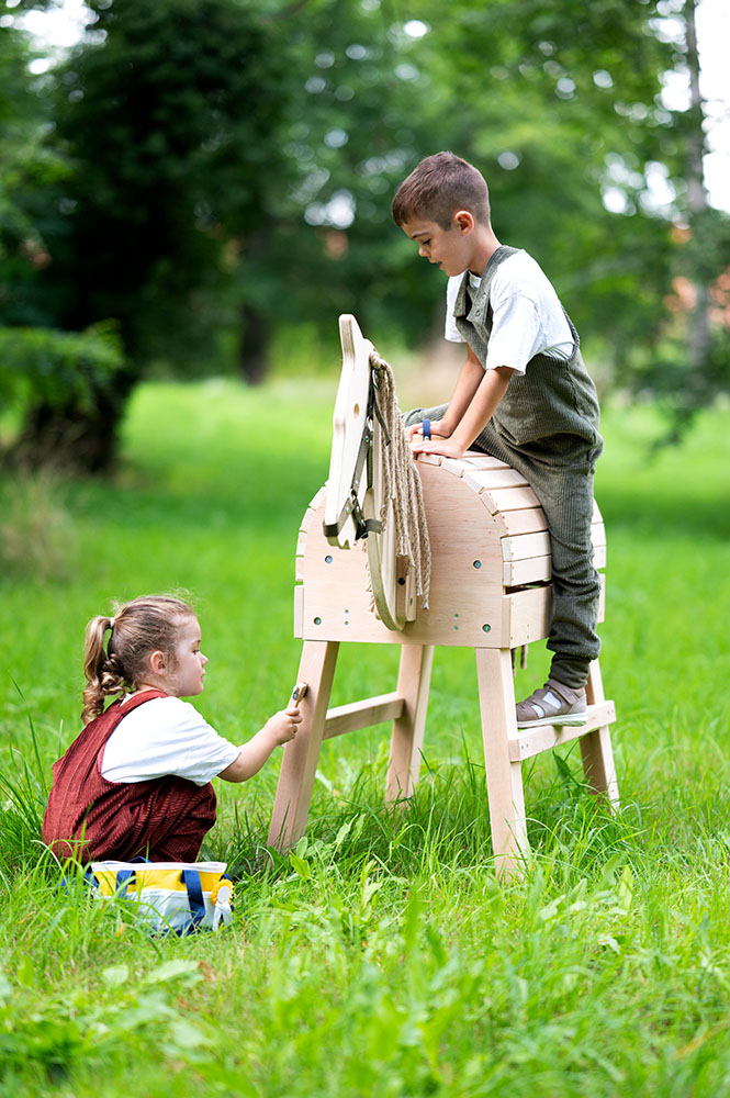 Kind pflegt Spielzeugpferd mit Tasche