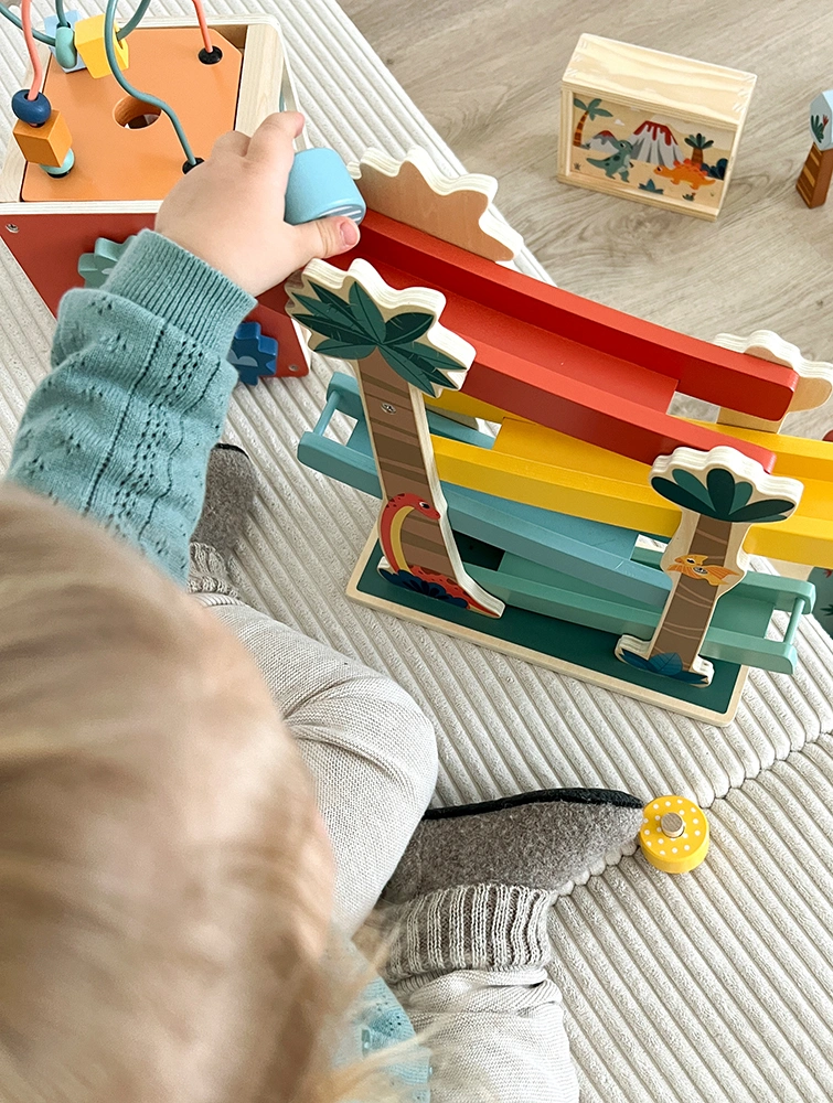 Kind spielt mit Dino-Rennbahn aus Holz