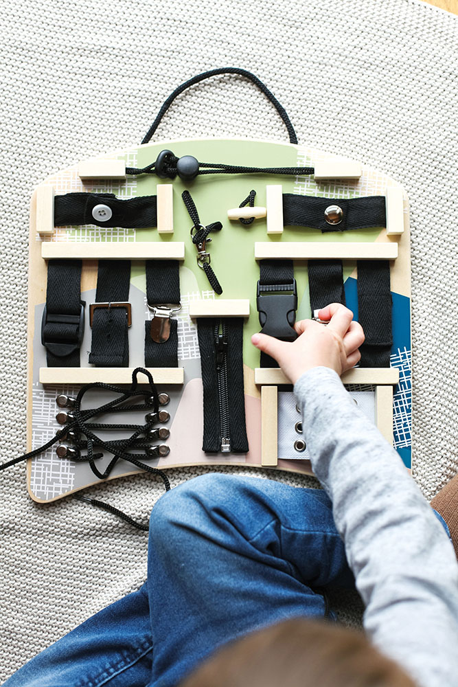 Kind spielt am Motorikbrett Verschlüsse