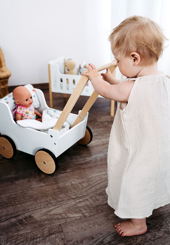 Kind spielt mit Schiebe- und Puppenwagen Little Button