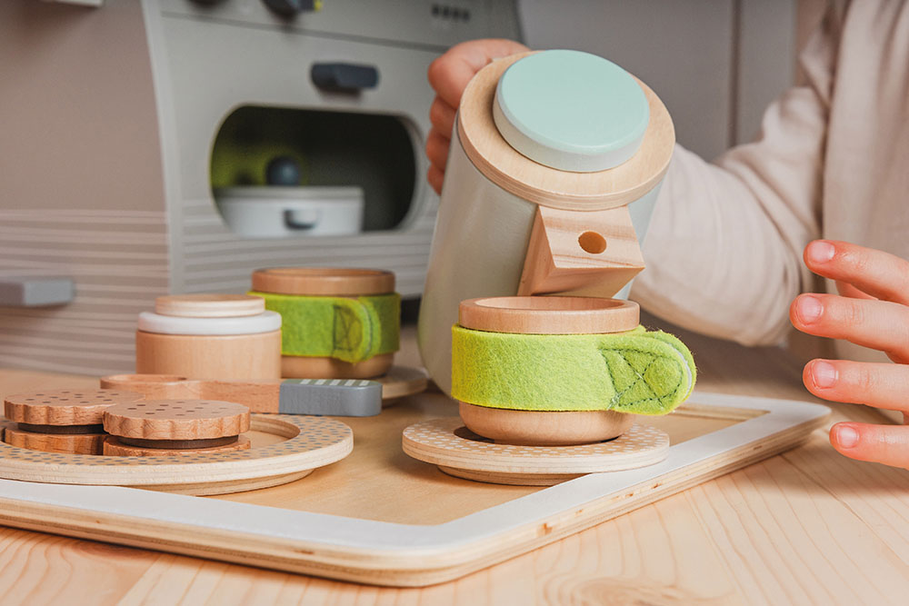 Kind spielt mit Kaffee- und Tee-Set Kinderküche