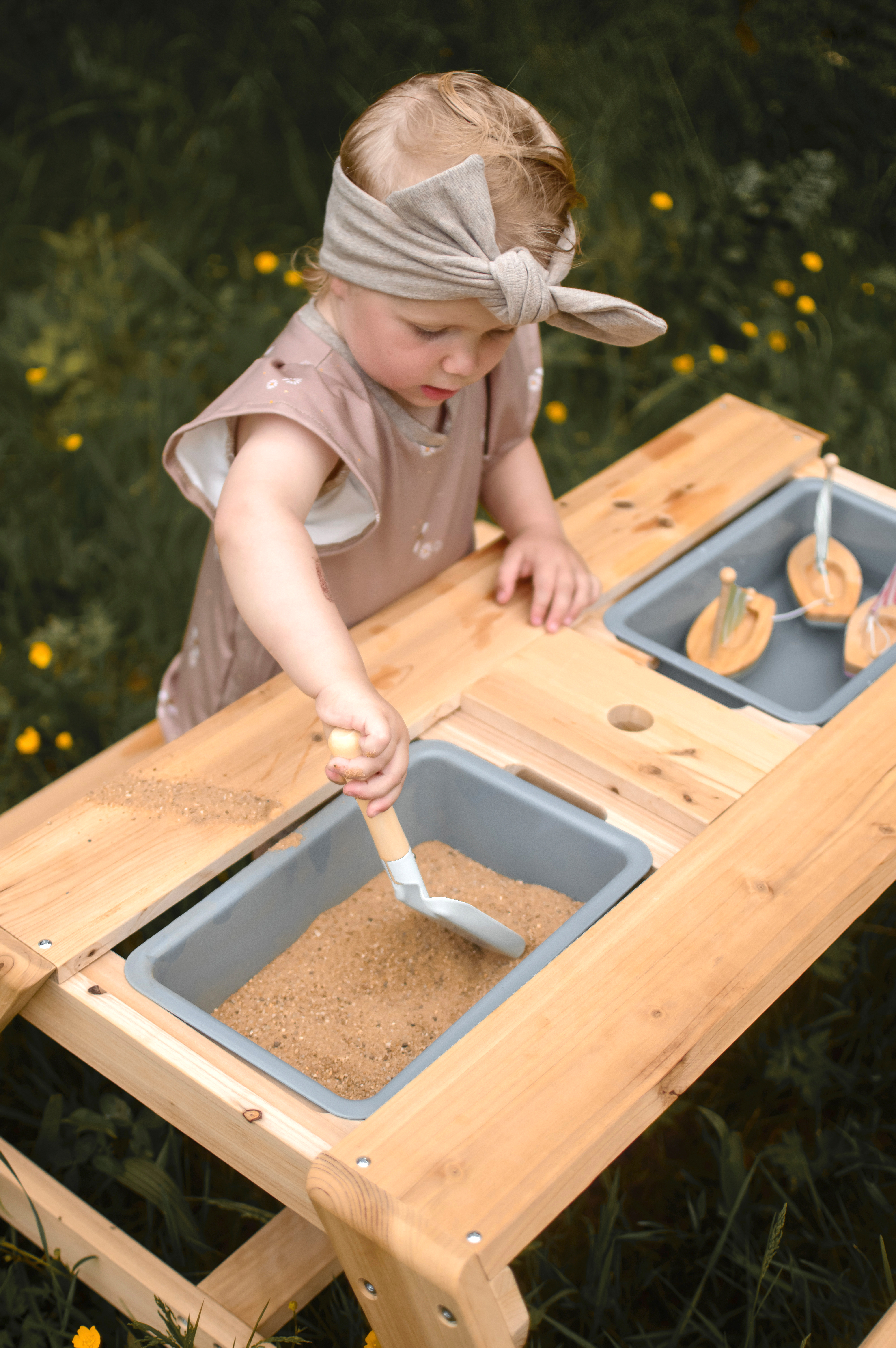 Kind spielt mit Kindersitzgruppe Matschtisch