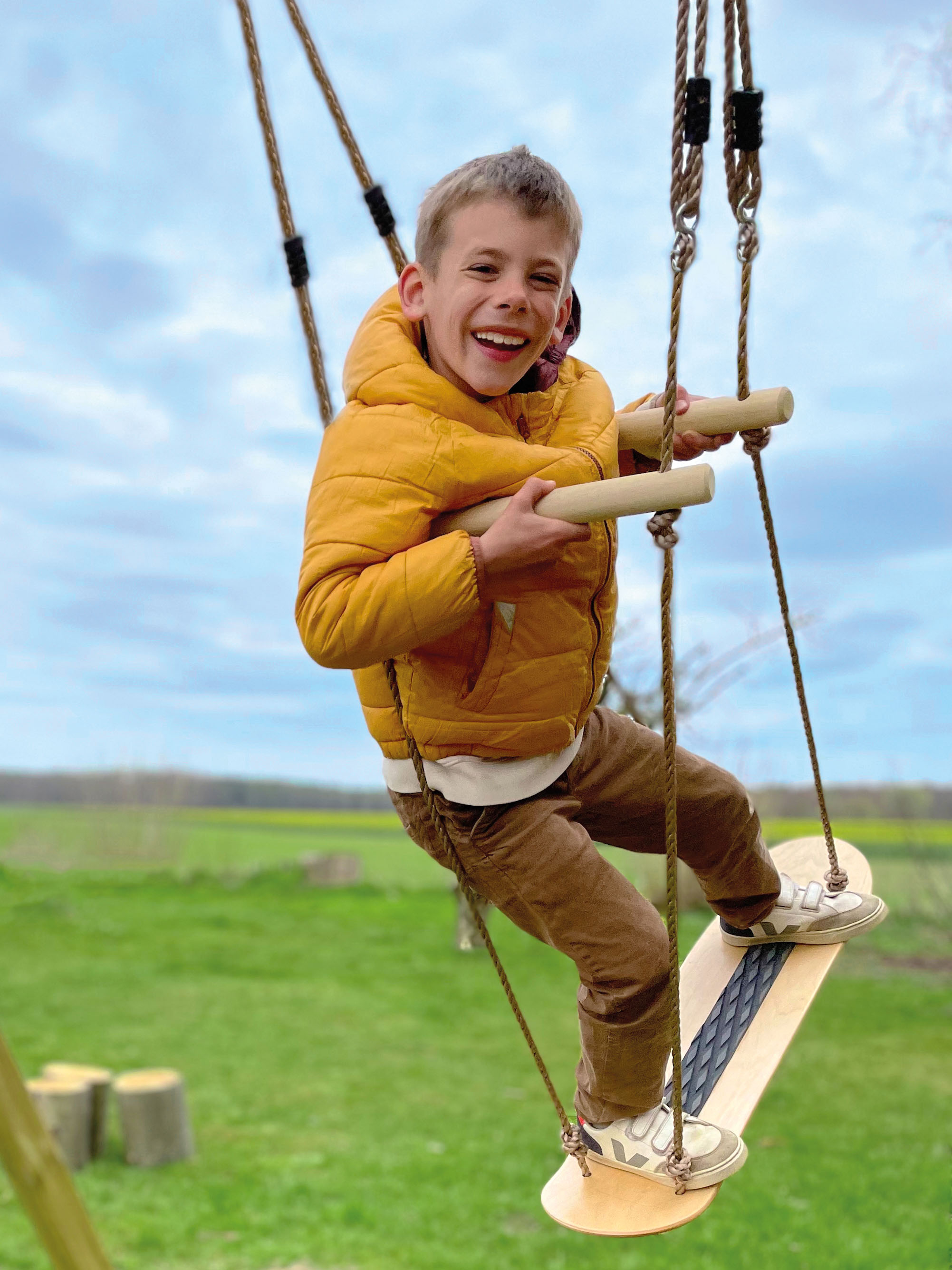 Junge auf Skateboard-Schaukel mit Haltegriffen